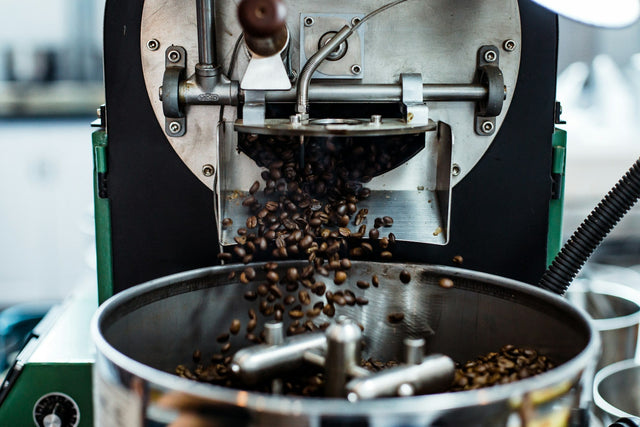 Freshly roasted coffee beans dropping from a roaster into the cooling tray