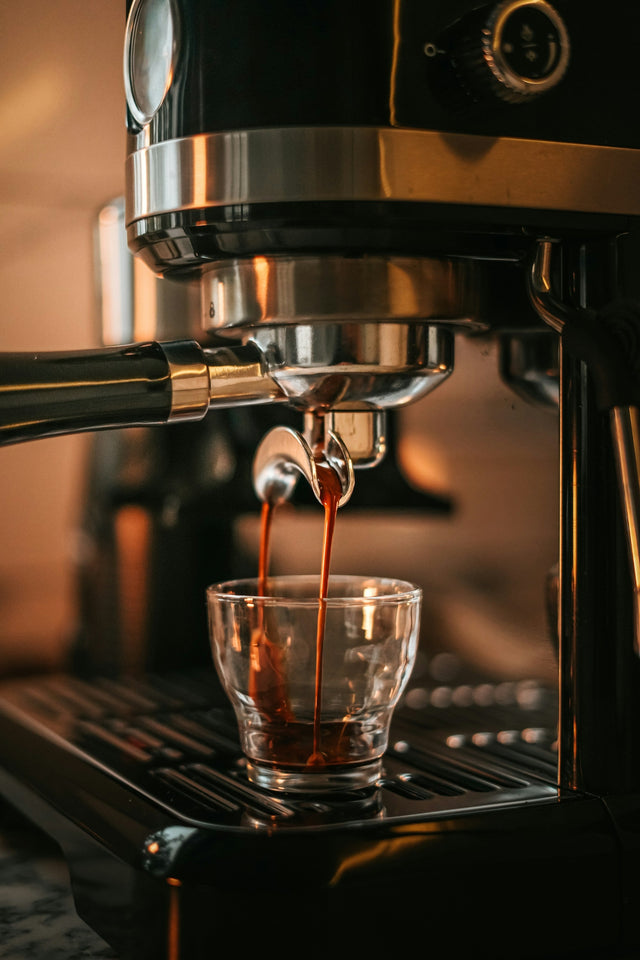 Espresso shot pouring from a machine into a small glass