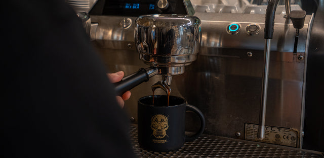 Espresso shot pouring from a portafilter into a glass