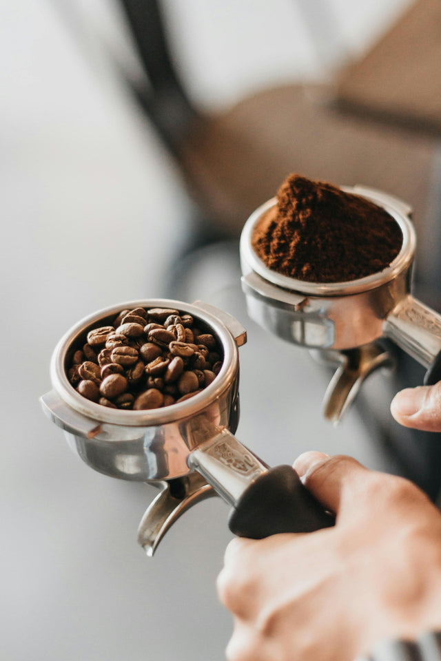 Two portafilters, one holding whole coffee beans and one holding ground coffee